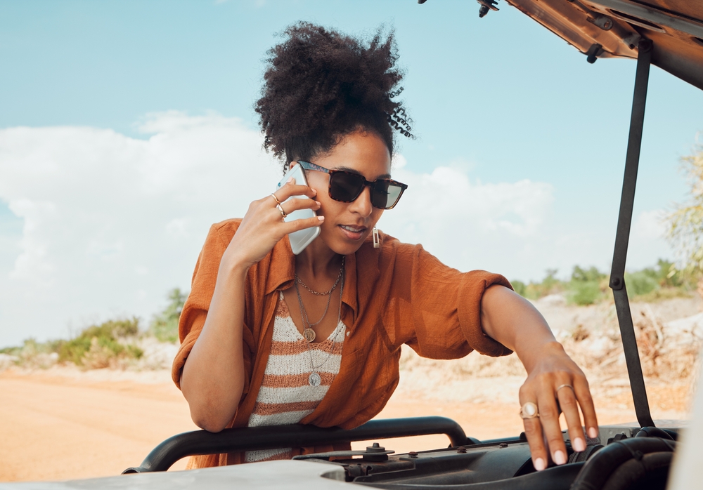 woman calling roadside assistance while fixing car