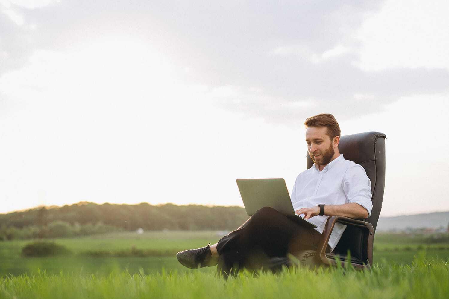 man working on laptop in green field