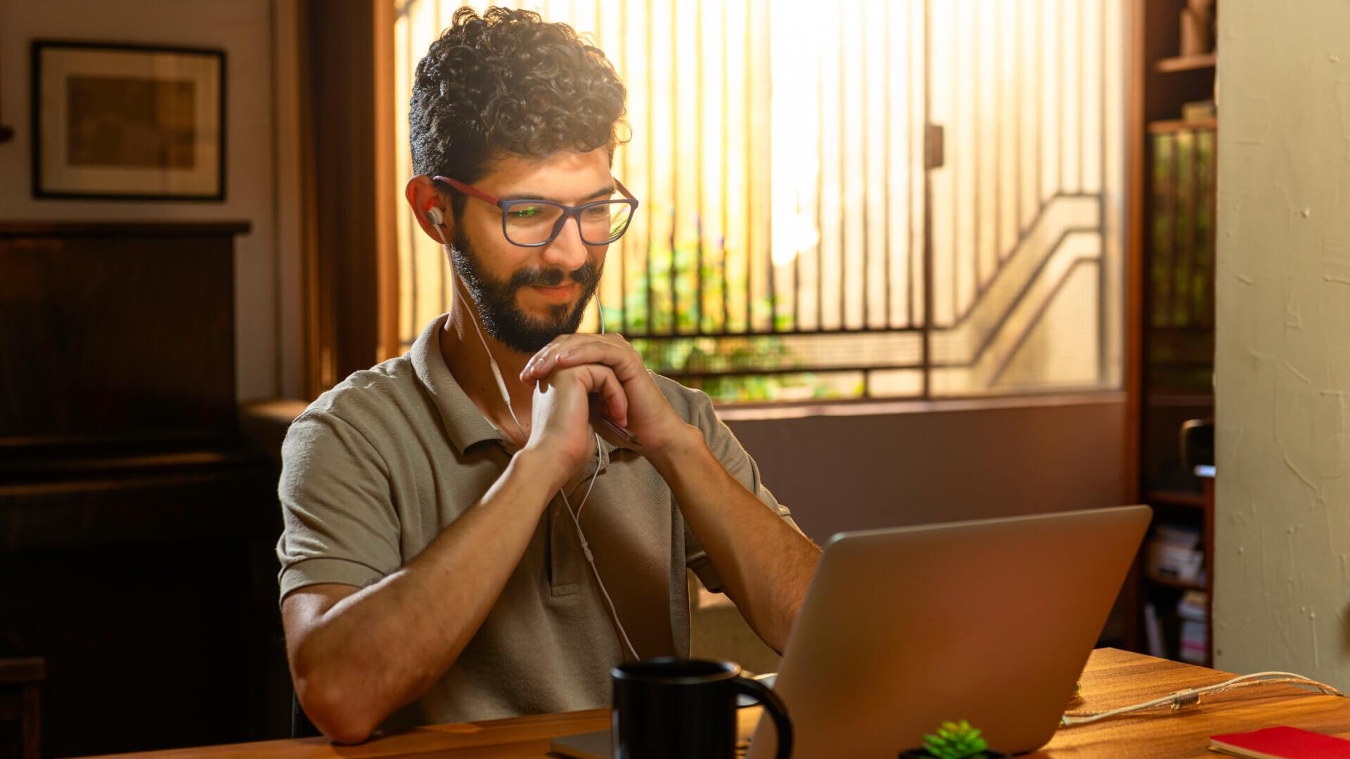 man wearing headphones smiling at computer screen