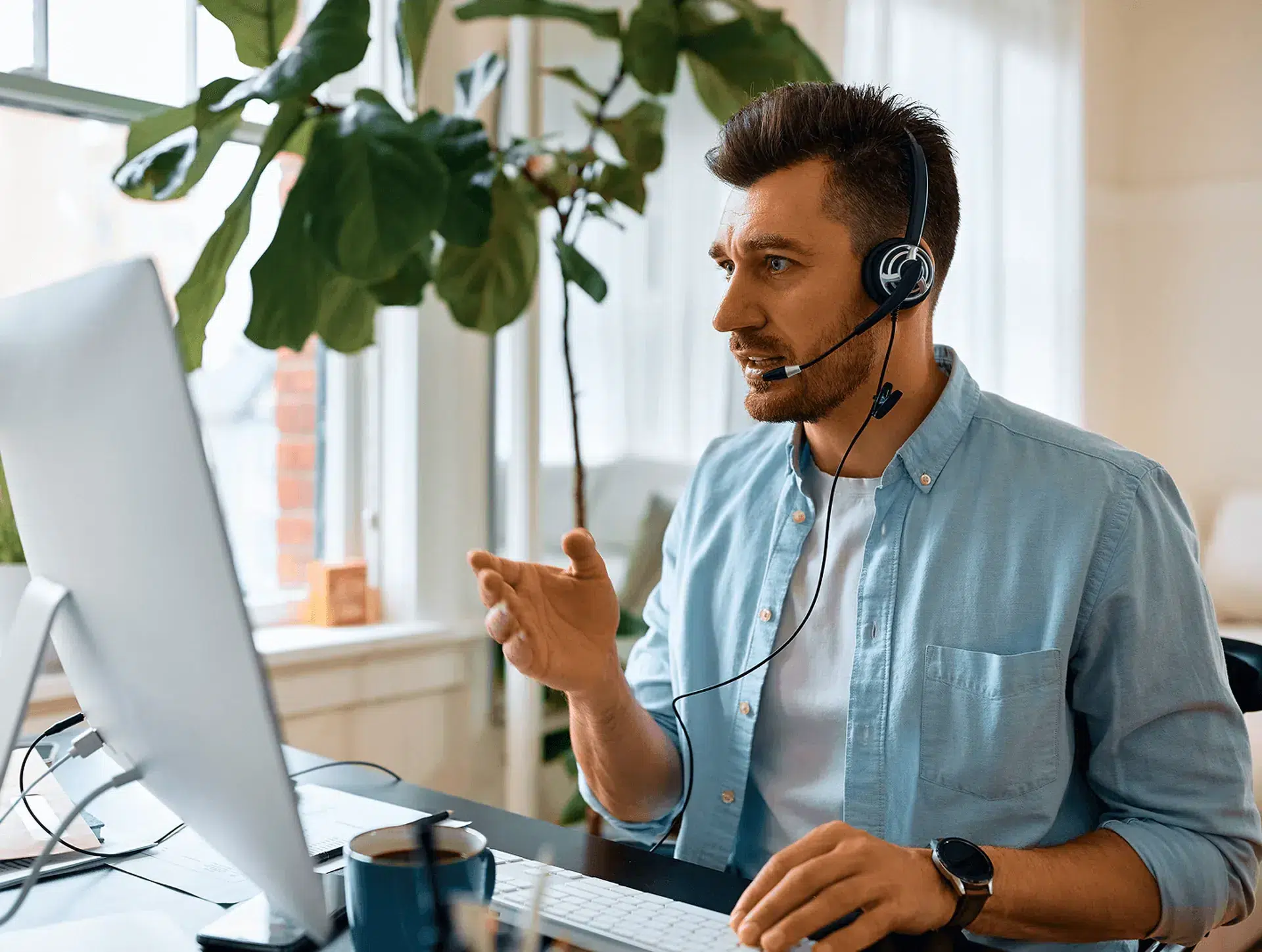 man wearing a headset smiling while working from home on a video call