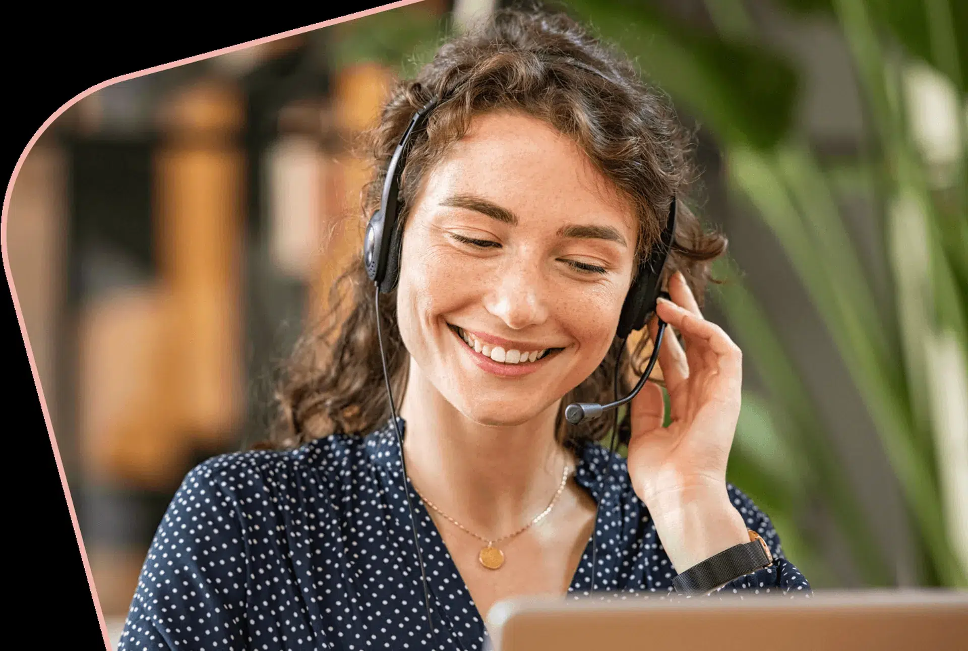 http://woman%20smiling%20while%20wearing%20a%20headset%20and%20looking%20at%20her%20computer
