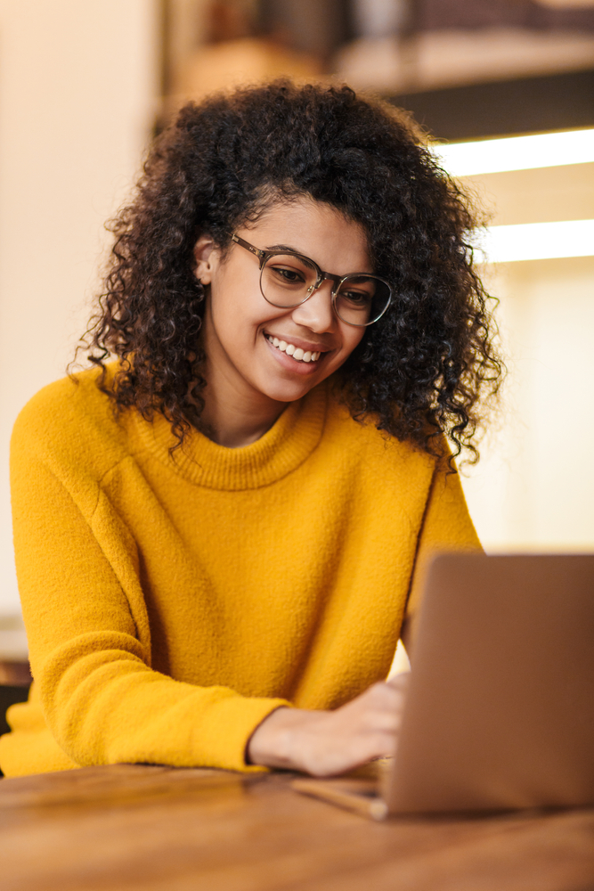 Woman smiling and working on laptop illustrating AI discovery and roadmap planning.